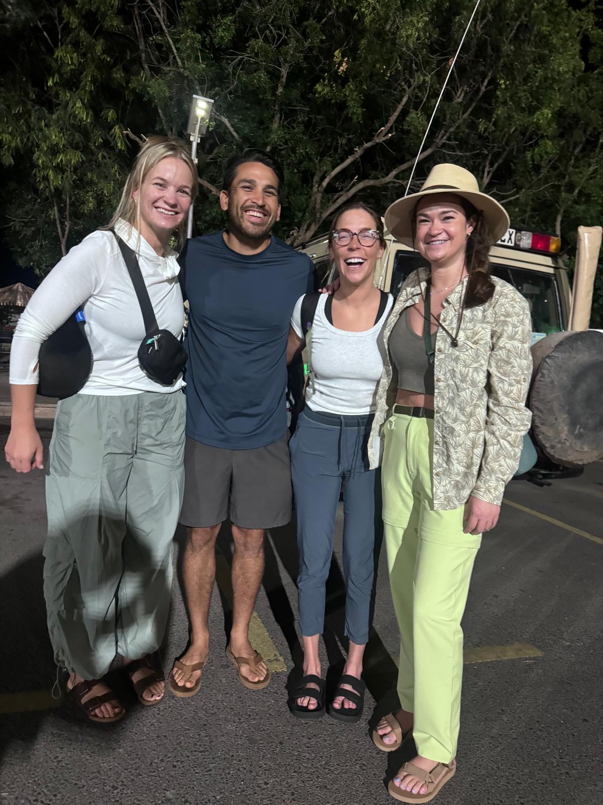 A smiling group of Reed Safari travelers gathered beside a safari vehicle