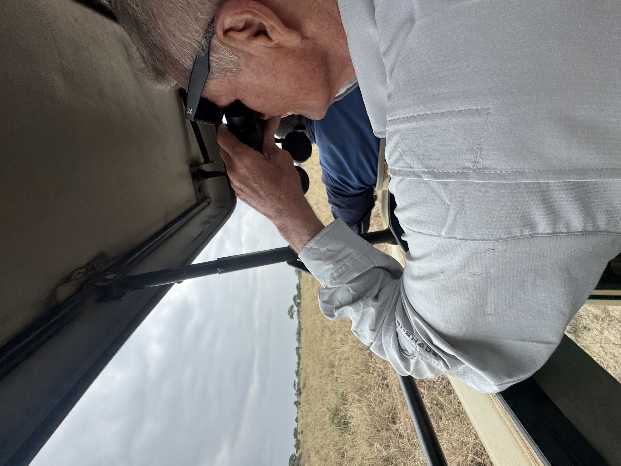 Reed Safari guest looking across the Tanzanian plains through binoculars