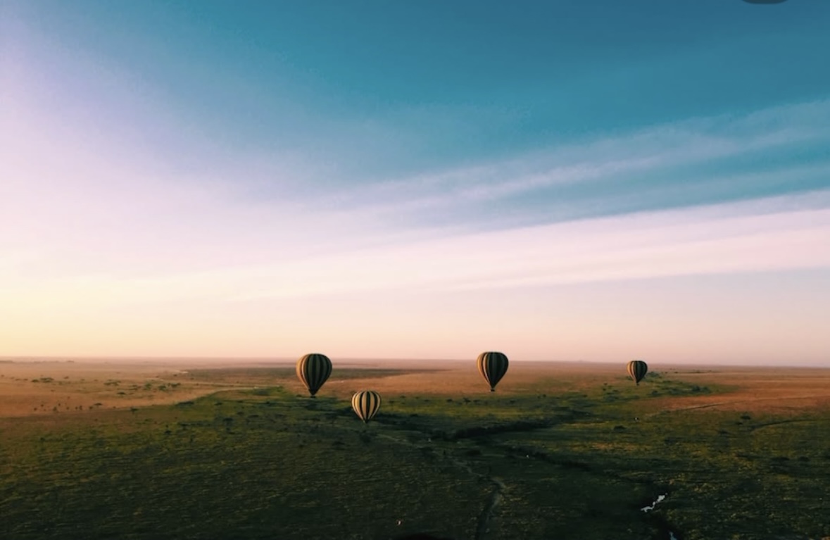 Hot air balloons floating above the Serengeti at sunrise
