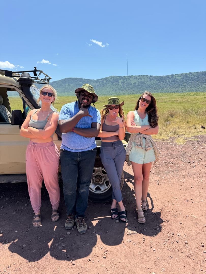 Reed Safari guests with their Tanzanian safari guide beside the safari vehicle